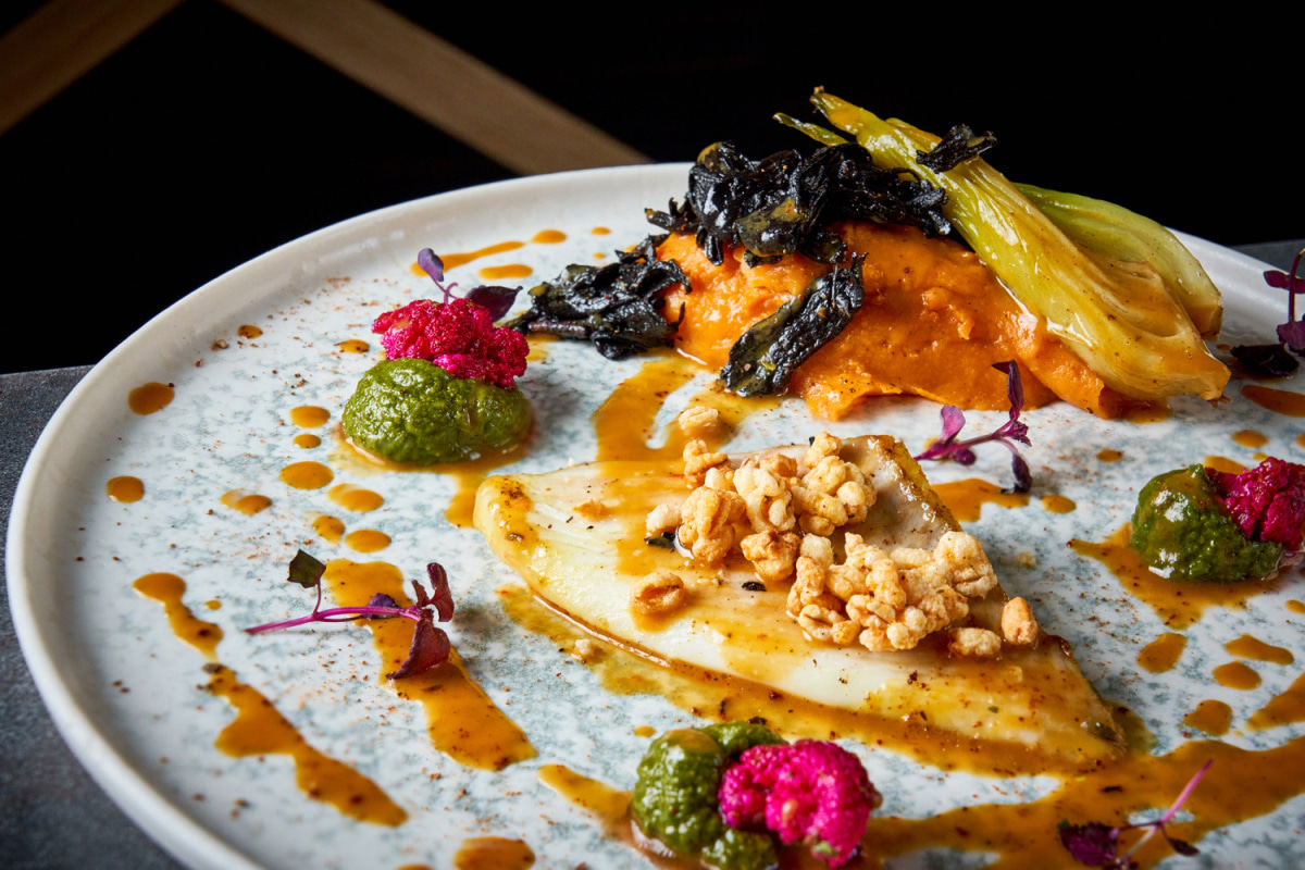 Assiette dressée avec sauces colorées et fleurs comestibles